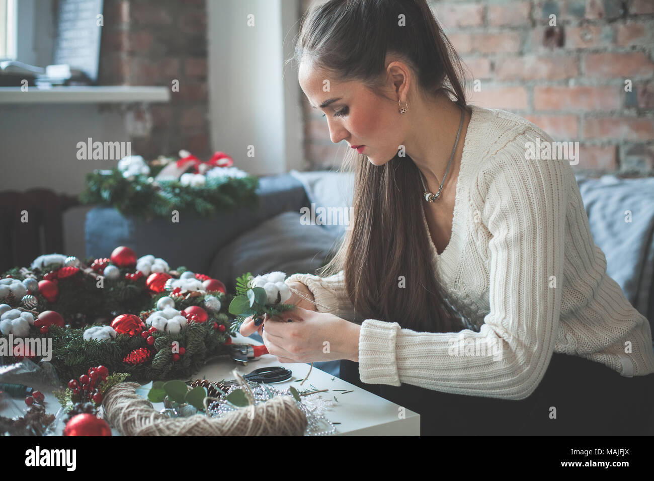 Ragazza carina decoratore con decorazioni natalizie e strumenti di fiorista Foto Stock