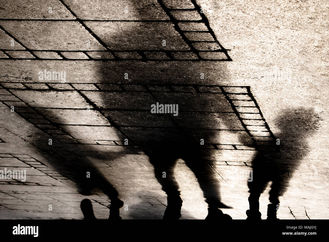 Silhouette ombra di un padre tenendo le mani con due bambini piccoli figli sul marciapiede della città in seppia in bianco e nero Foto Stock