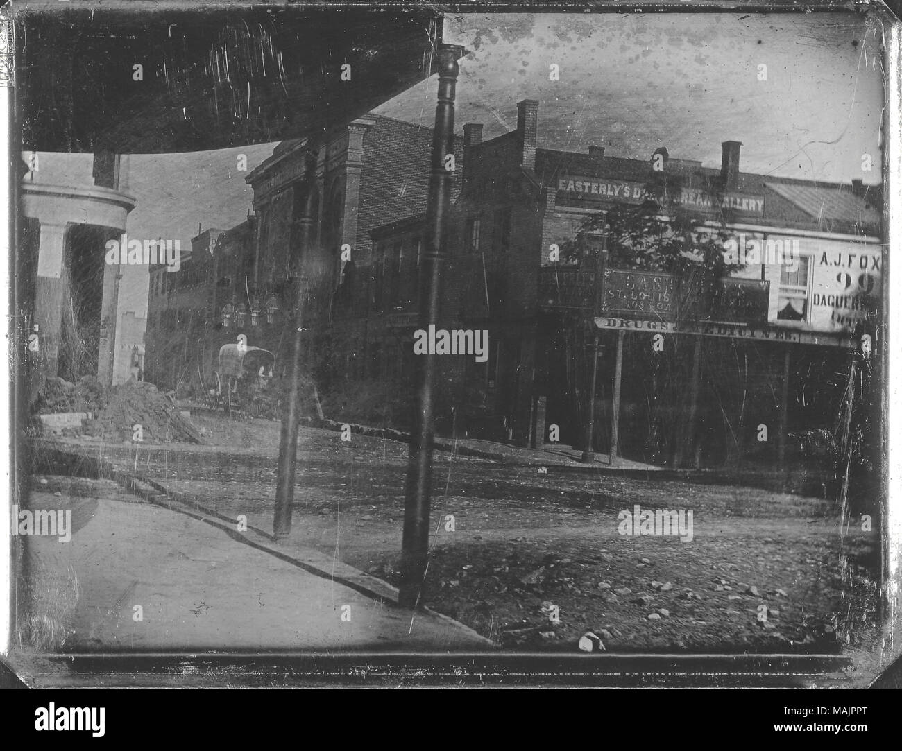 Vista Est Daguerrean della galleria su angolo sud-est di quarta e di strade di oliva. Ad est la galleria è al piano superiore dell'edificio ad angolo e ha segni la lettura "dell'Est San Louis Daguerrean Gallery' e dell'Est ST. Louis Daguerrean 203 Gallery 203'. Il negozio sotto la galleria al primo piano ha un segno sul suo portico che recita "droga e di medicina". Un uomo alla guida di un cavallo e un carro è sulla strada e molti altri edifici commerciali può essere visto. Una tenda con due pali fissati al marciapiede sono in primo piano e sono di fronte alla strada dalla Gallery. Un mucchio di d Foto Stock
