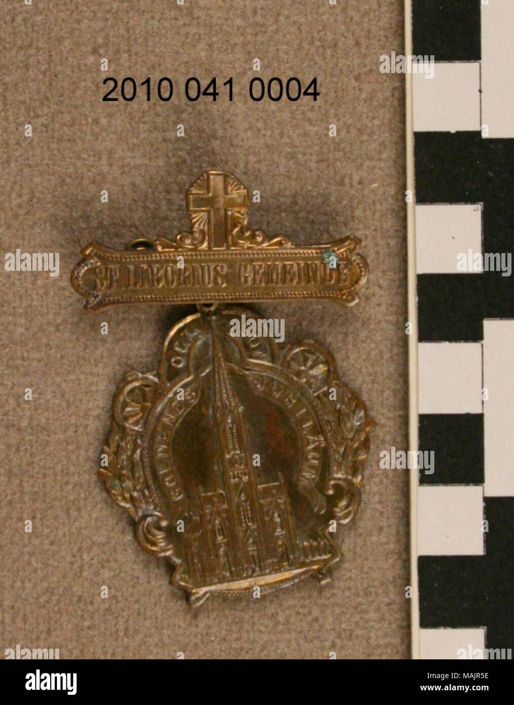 Medaglia di bronzo con il pin sul retro della parte superiore. Croce al top. La parte inferiore si blocca da anello agganciato alla barra sul retro della parte superiore. La parte inferiore mostra una chiesa circondata da un motivo vegetale a destra e a sinistra. Titolo: 1907 San Liborius Gemeinde Medal . 1907. Foto Stock