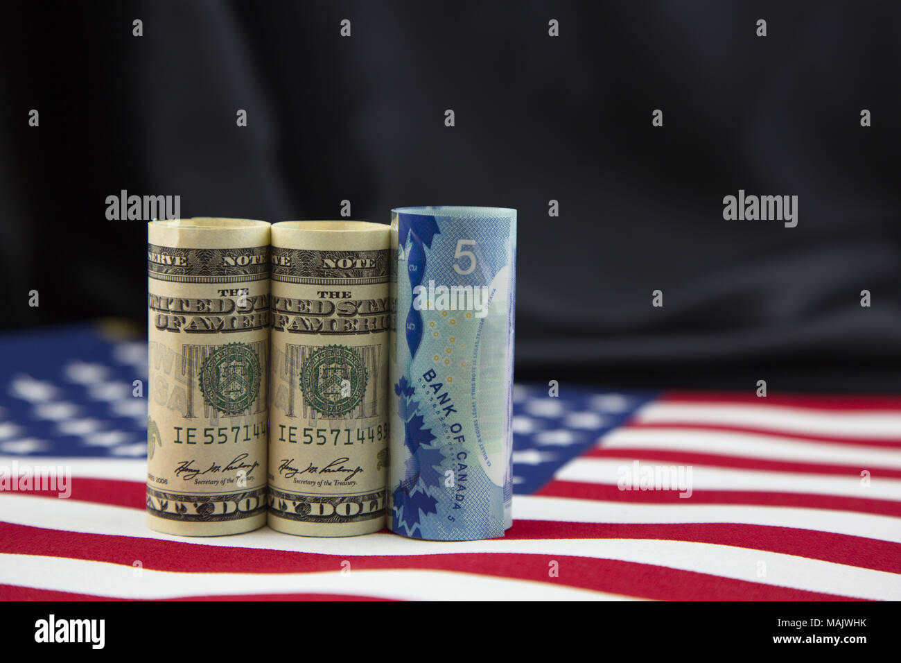 Le monete nazionali di Stati Uniti e Canada sono collocati su una bandiera americana contro accento di satin nero lo sfondo. Foto Stock