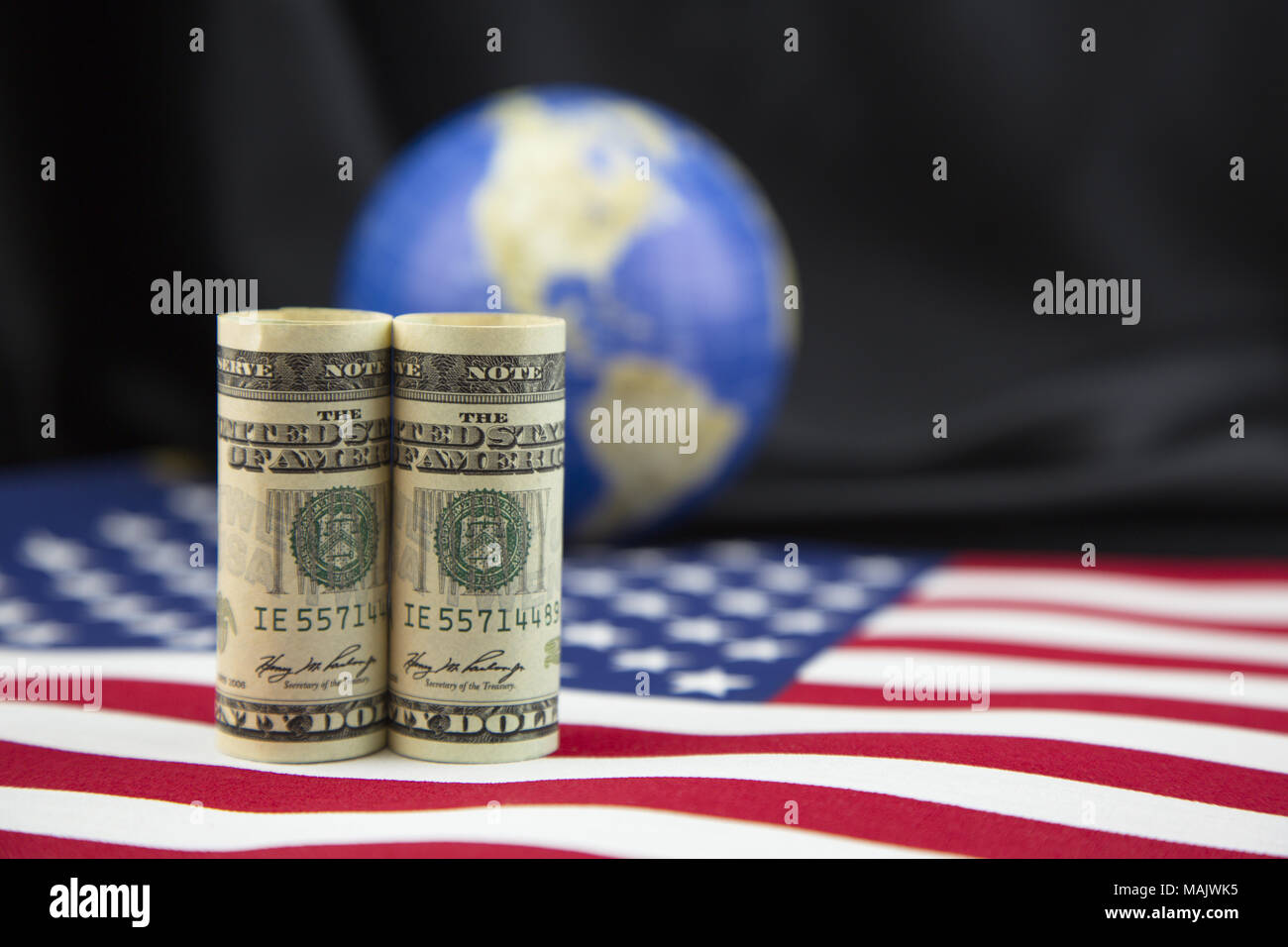 Focus sulla moneta americana posto sulla bandiera nazionale con unfocused satin nero e sfondo del globo in profondità di campo. Simboli di American pol Foto Stock