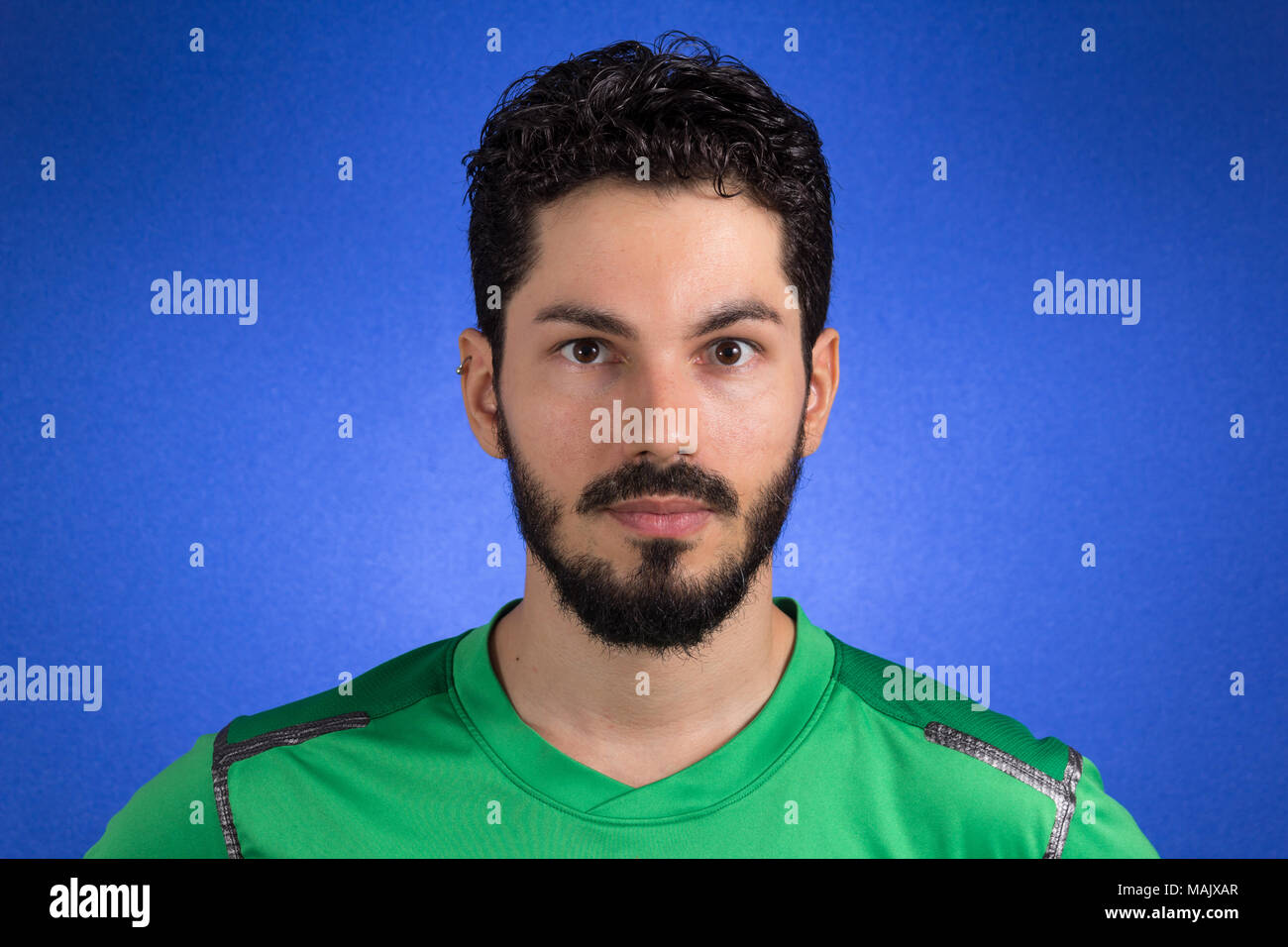 Calcio brasiliano giocatore di calcio. Un sostenitore e ventola guardando fiduciosi. Usura uniforme verde su sfondo blu. Foto Stock