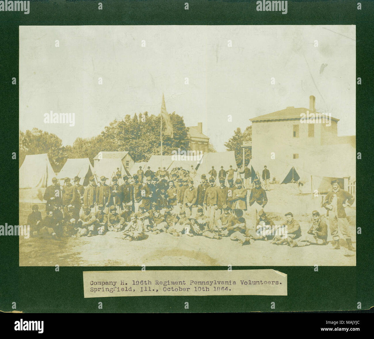 Foto di gruppo di unione i soldati in uniforme in primo piano e una bandiera europea su un pennone, tende e gli edifici in background. "Azienda H. 196th reggimento volontari della Pennsylvania. Springfield, Ill., 10 ottobre 1864." (tipo di immagine sotto). "Da H. F. Geyer Lt Co H Dec 1907' (scritta sul lato inverso). 1Lt. Henry F. Geyer è elencato nel digital soldati record come avente apparteneva a questa società e il reggimento. Egli può essere il funzionario che è seduto al centro del gruppo direttamente sotto la bandiera della pole. Titolo: Azienda H. 196th reggimento volontari della Pennsylvania. Springfield, Ill., Foto Stock