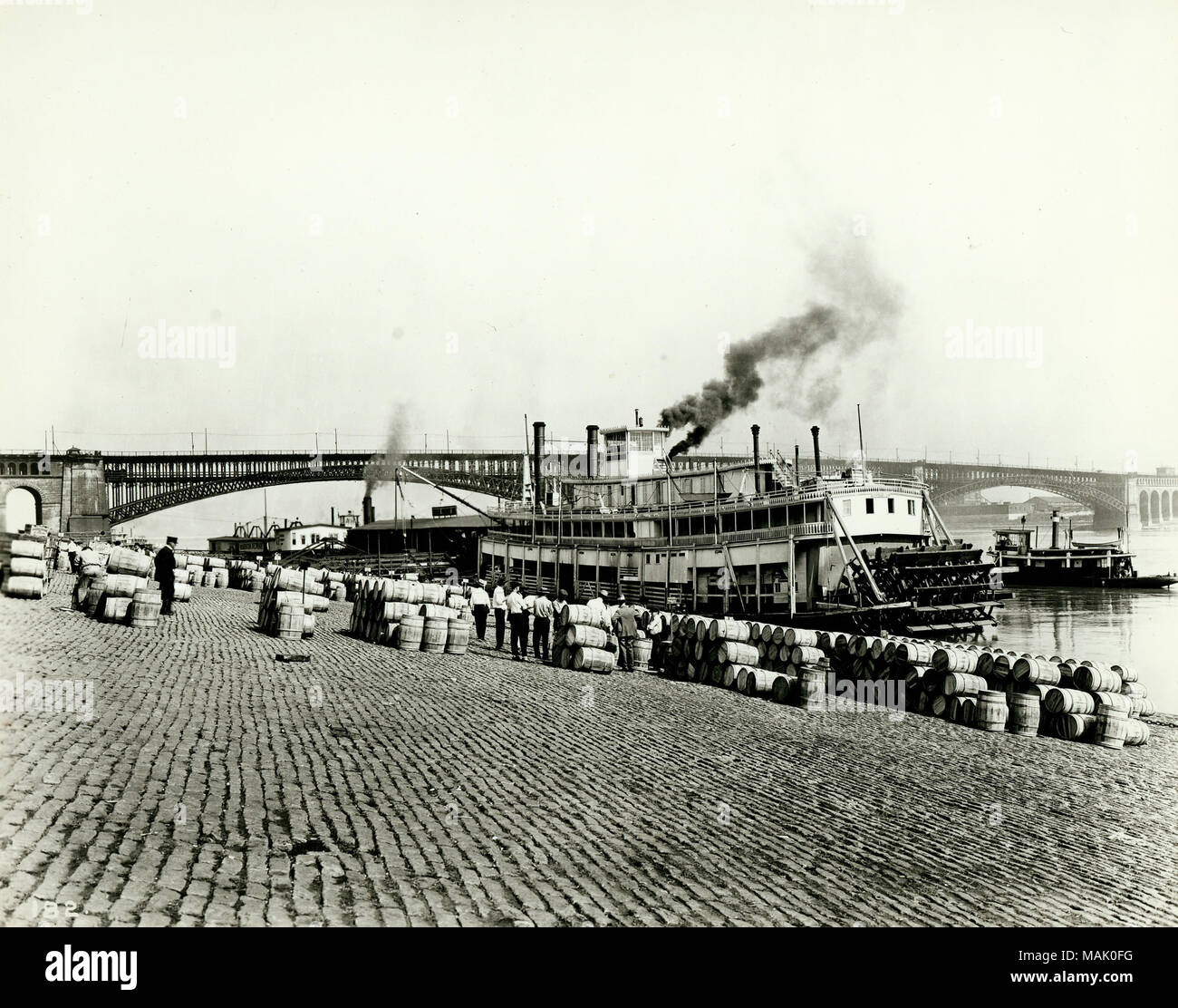 Barili di Calhoun County mele venga scaricato sulla San Louis argine. Il Levee era centrale a San Louis' economia dalla città di fondazione e ha raggiunto il suo picco nel mid-1800s quando più di 600 piroscafi erano operanti lungo le sue rive. La guerra civile isolato San Louis dai mercati del sud e diviso la città degli affari e leader politici. Attività sull'argine diminuita come steamboat il traffico è diminuito e ferrovie ha iniziato a dominare la navigazione commerciale. Titolo: tempo di Apple sull'argine a St. Louis. [Barili di Calhoun County mele essendo scaricati sull'argine]. . 1919. Il W.C. Persone Foto Stock