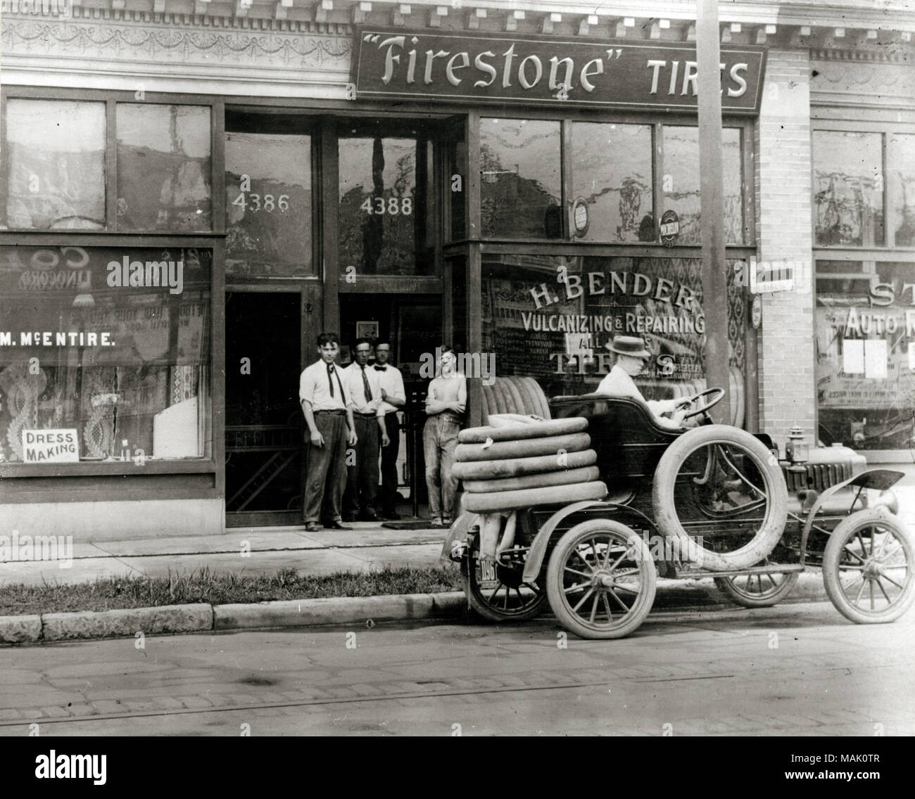 Gli uomini in automobile e la riparazione di pneumatici truck raccolte al di fuori del H. Bender Firestone pneumatico concessionaria a Oliva 4388] Street. La finestra storefront pubblicizza, 'la vulcanizzazione e la riparazione di tutte le marche di pneumatici'. I fabbricanti di automobili, nelle officine di riparazione e le concessionarie iniziarono ad aprire nella città di inizio Novecento. Dal 1908 la città di San Luigi aveva emesso 1.900 licenze di automobile. Titolo: Automobile per la riparazione dei pneumatici al di fuori del carrello H. Bender Firestone pneumatico concessionaria. 4388] Strada di oliva. 'La vulcanizzazione e la riparazione di tutte le marche di pneumatici." . 1906. Foto Stock