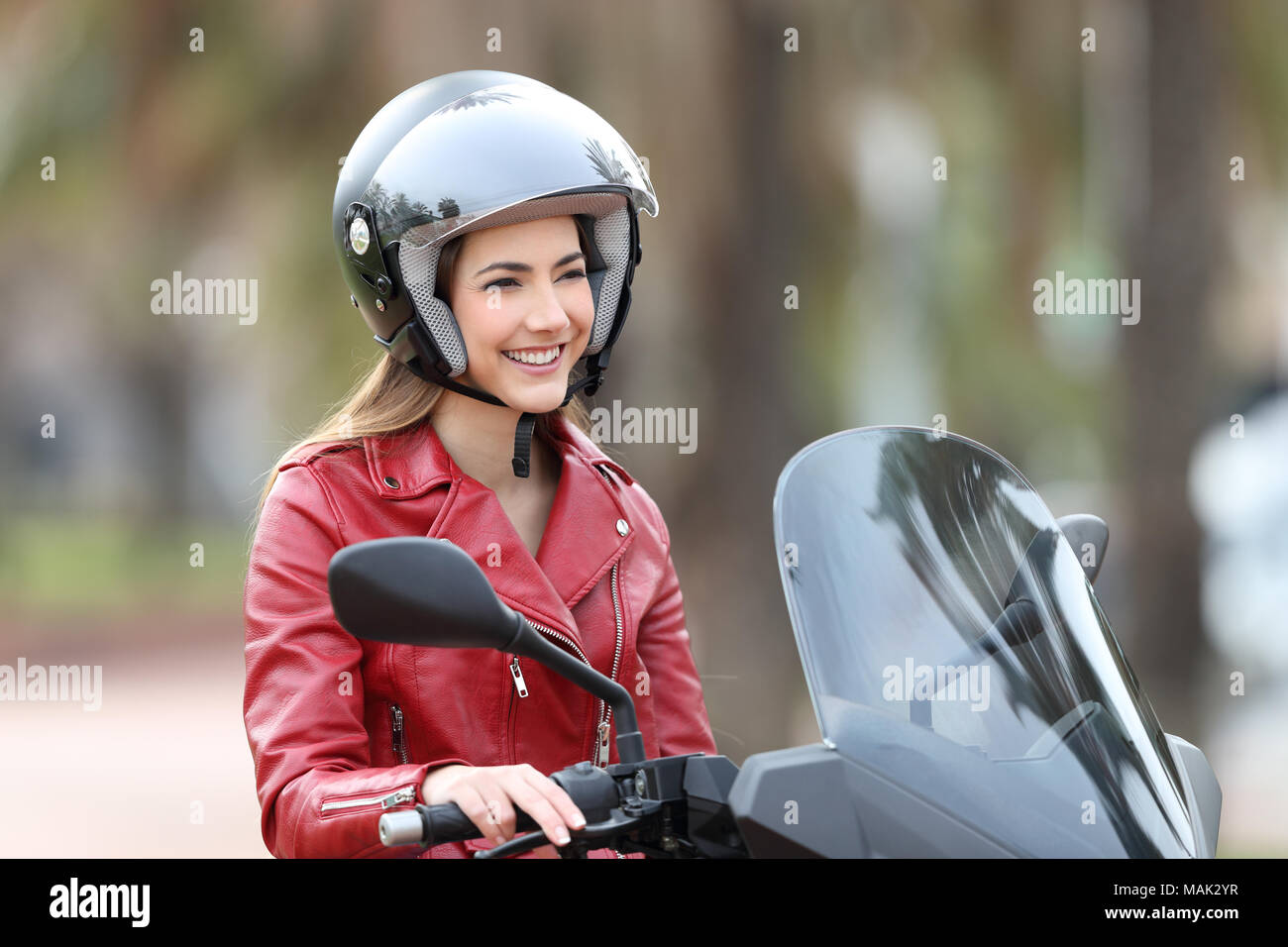 Felice biker seduto su una moto che guarda lontano sulla strada Foto Stock