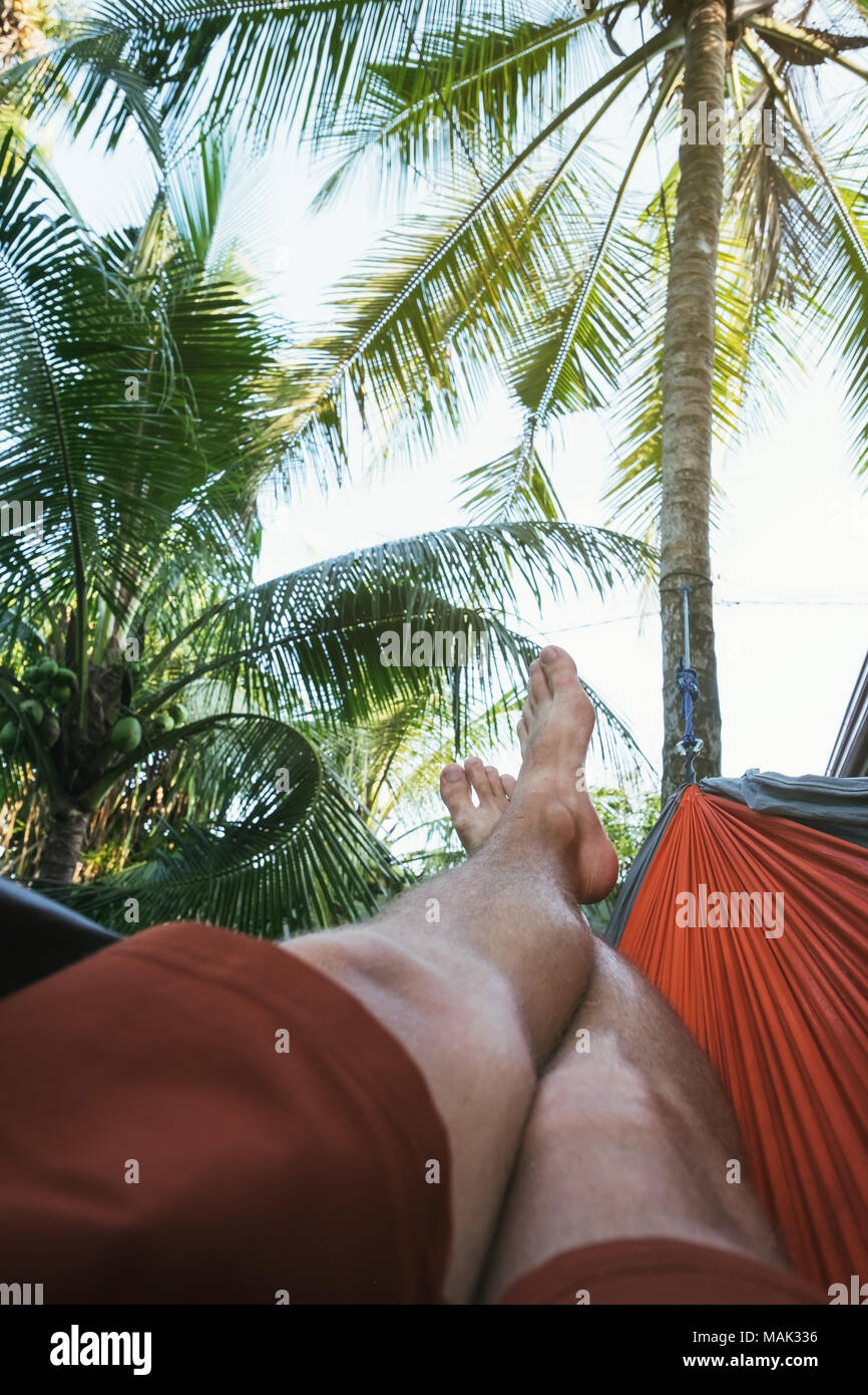 Gambe incrociate di uomo caucasico giacente in amaca e il riposo durante il tempo libero durante le vacanze Foto Stock