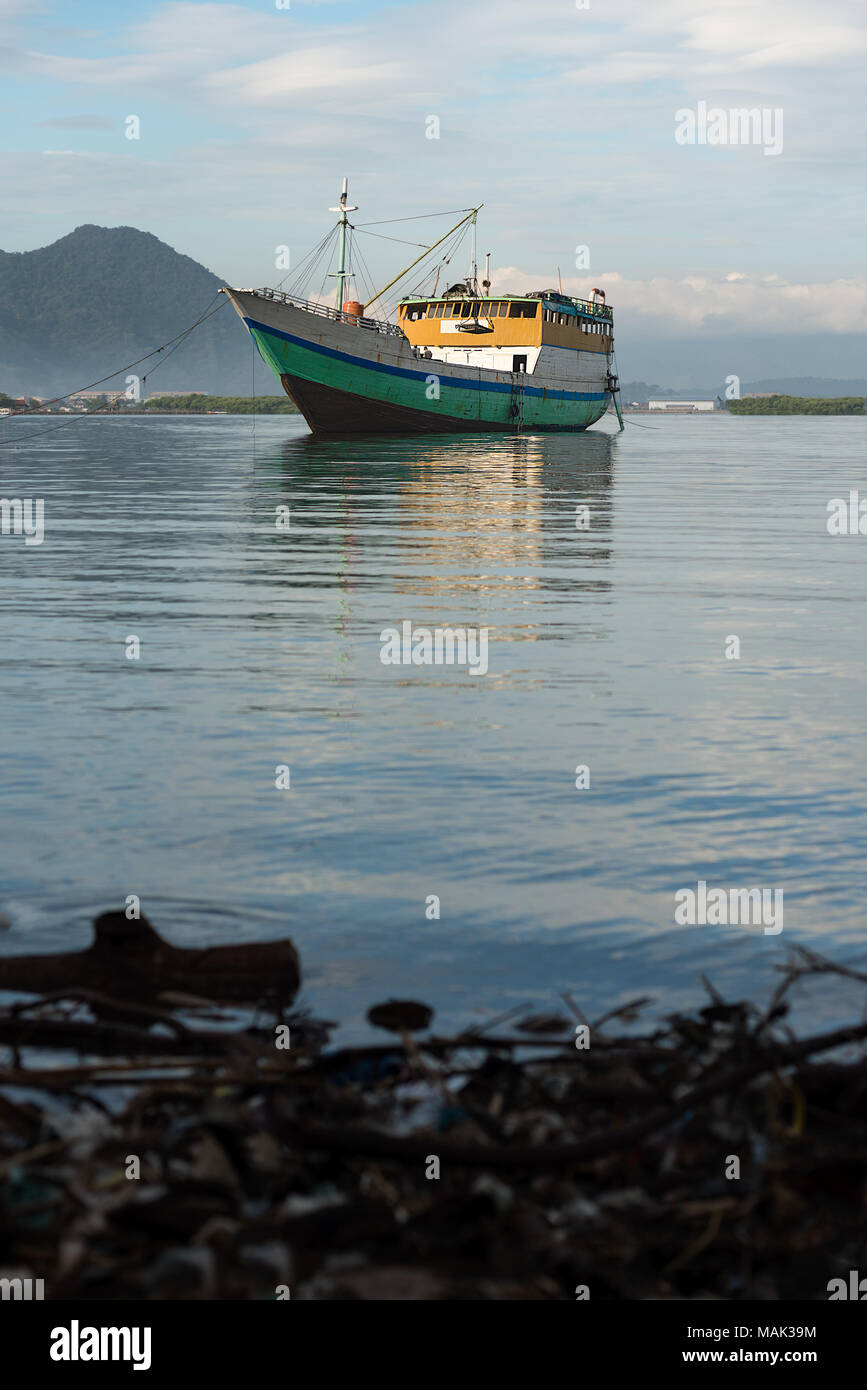 Grandi indonesiano in legno barca da pesca attende il suo giro in un mare calmo per una riparazione e restauro presso un cantiere navale sul bordo del BIMA, Sumbawa, Indonesia. Foto Stock