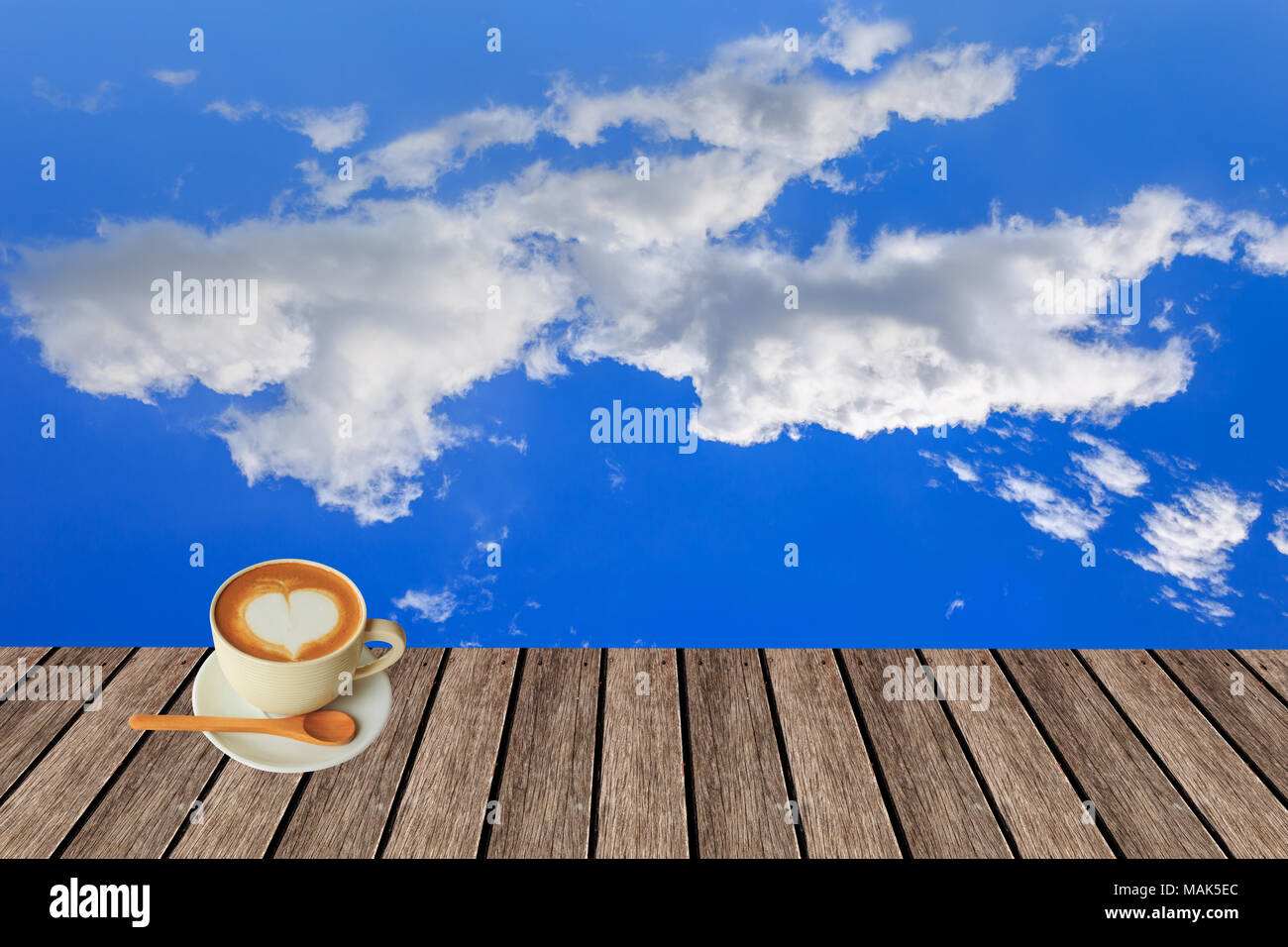 Forma di cuore nel caldo del cappuccino in legno cupon oltre il cielo blu e nuvoloso al giorno 12.00 sfondo luminoso Foto Stock
