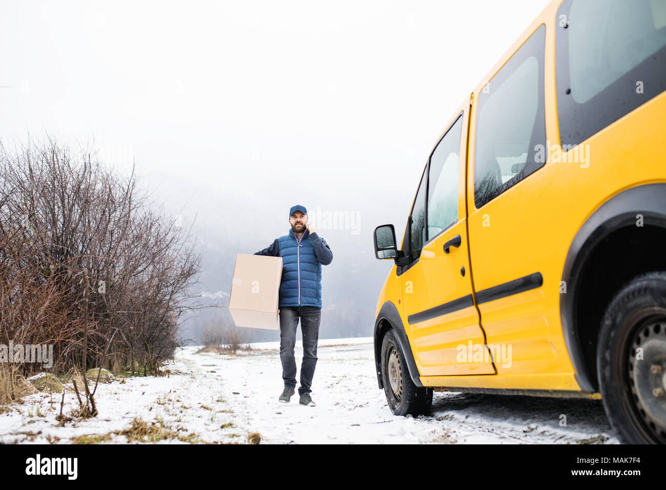 Uomo di consegna consegna pacchi a casella Destinatario. Foto Stock