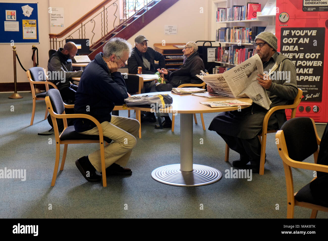I maschi nella zona di lettura di una biblioteca pubblica in Inghilterra, Regno Unito Foto Stock