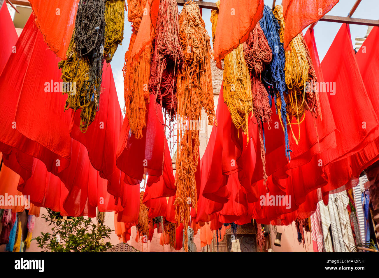 Il Marocco Marrakech Jemaa el Fna MEDINA SOUK tinto arancio e panno di lana multicolore appesi da poli di bambù per asciugare al sole Foto Stock
