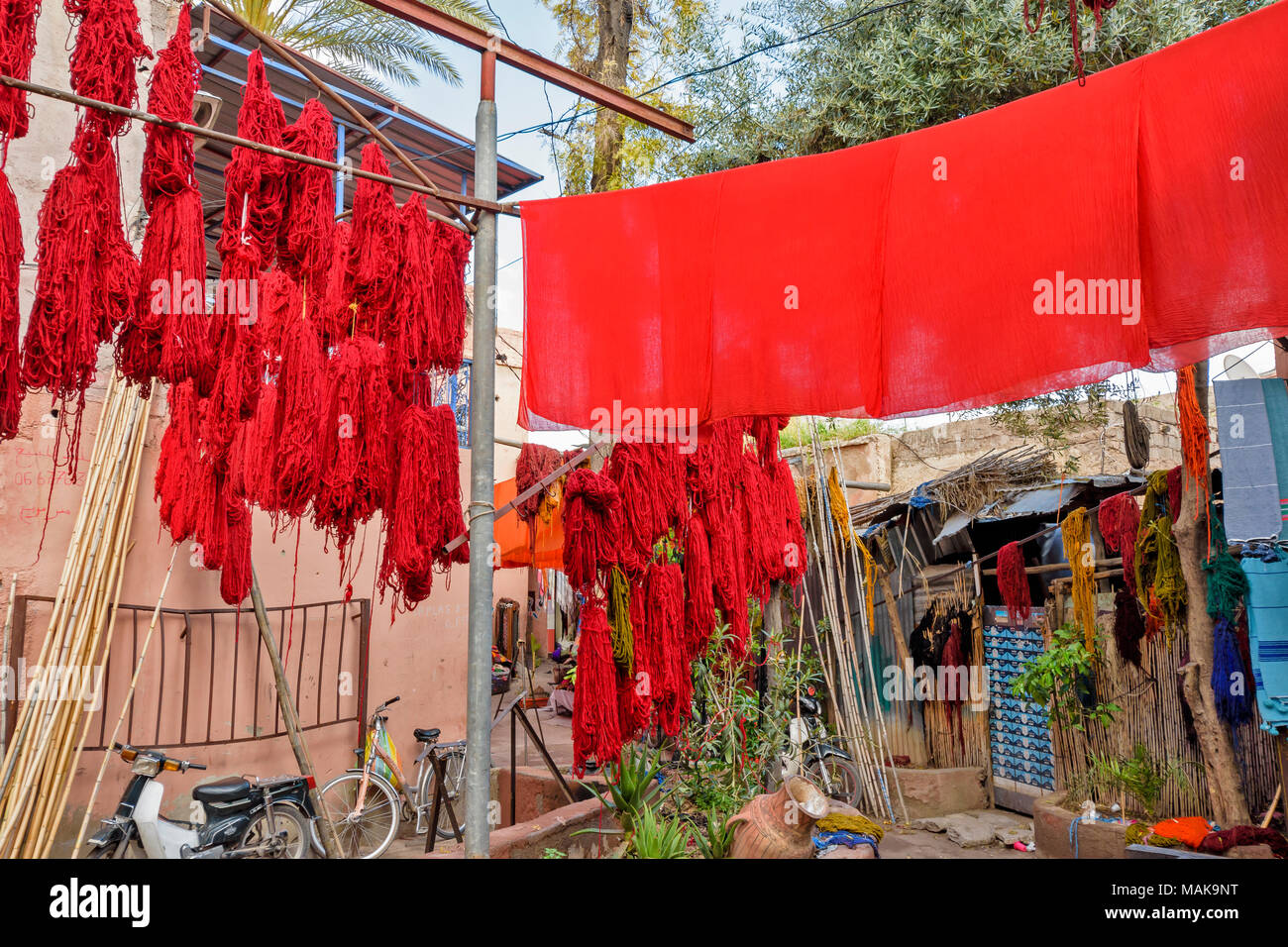 Il Marocco Marrakech Jemaa el Fna MEDINA SOUK arancione fogli tinti e lana multicolore appesi da poli di bambù per asciugare al sole Foto Stock