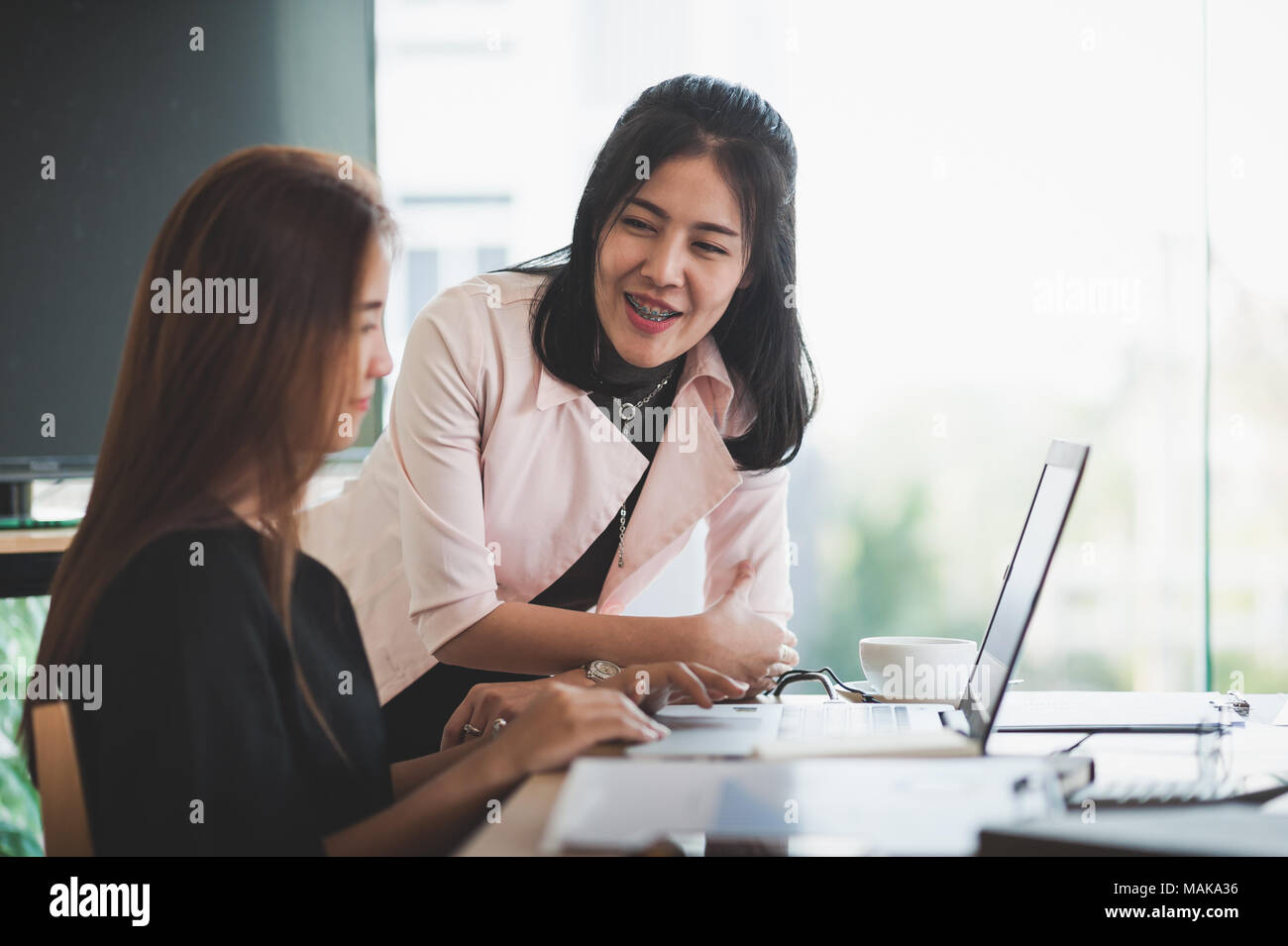 Giovani asiatici lavoratori aziendali che lavorano insieme con computer portatile in ufficio. Business di avvio al lavoro di squadra e il concetto di brainstorming Foto Stock