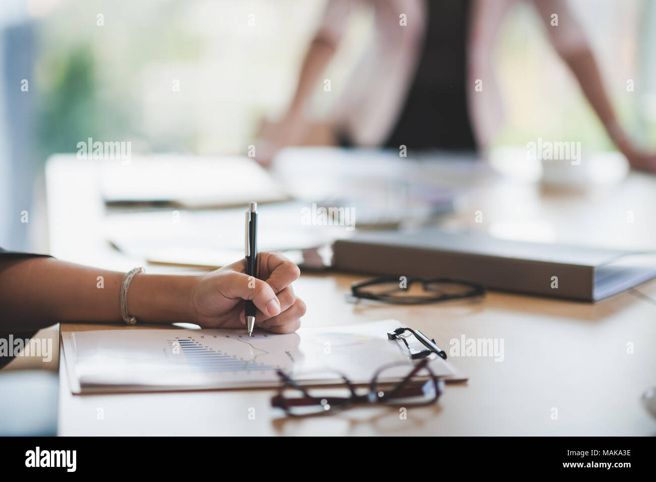La donna la scrittura a mano qualche idea sulla clipboard mentre è seduto in sala riunioni. Business lifestyle sulla giornata lavorativa Foto Stock