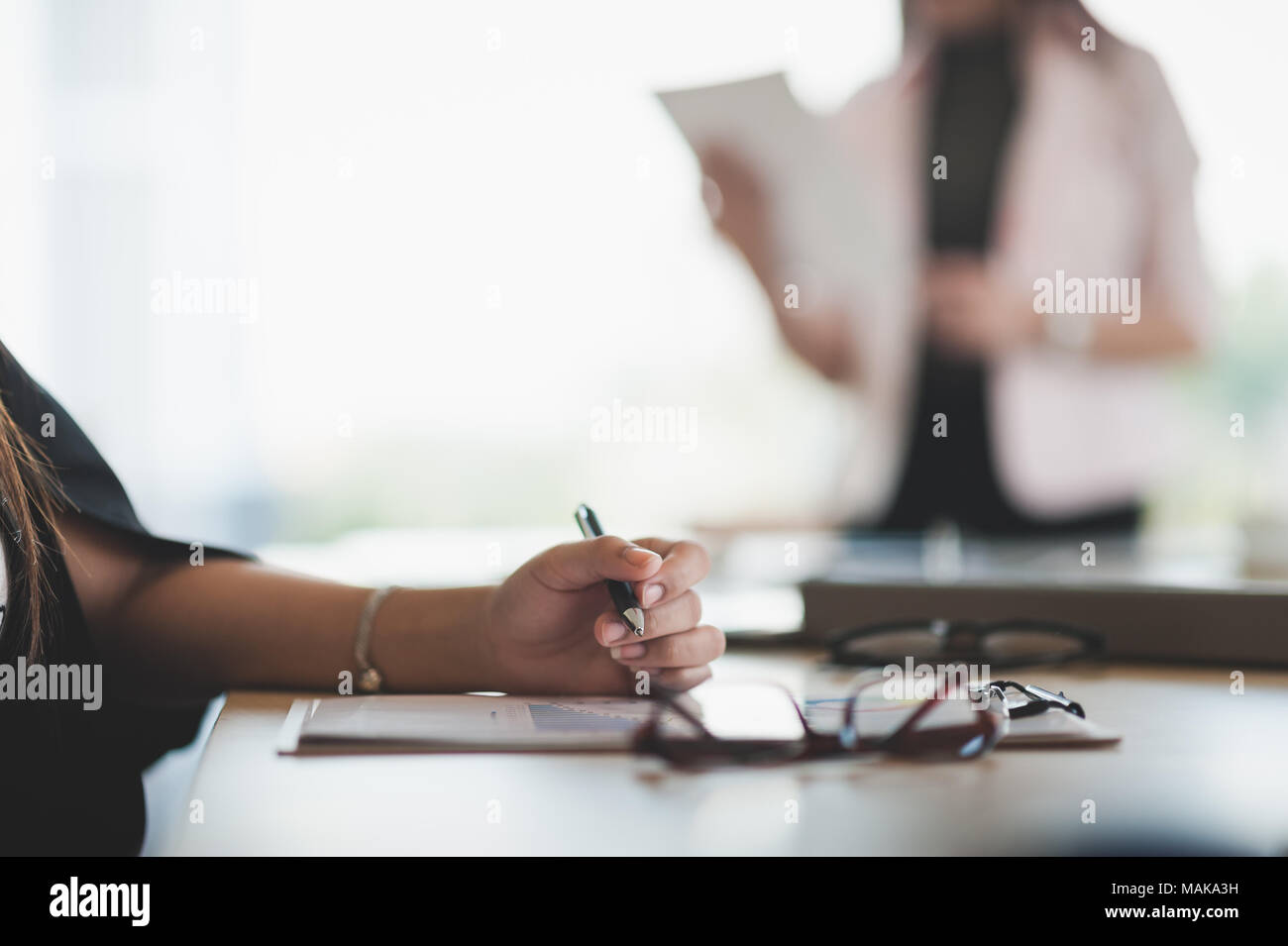 La donna la scrittura a mano qualche idea sulla clipboard mentre è seduto in sala riunioni. Business lifestyle sulla giornata lavorativa Foto Stock