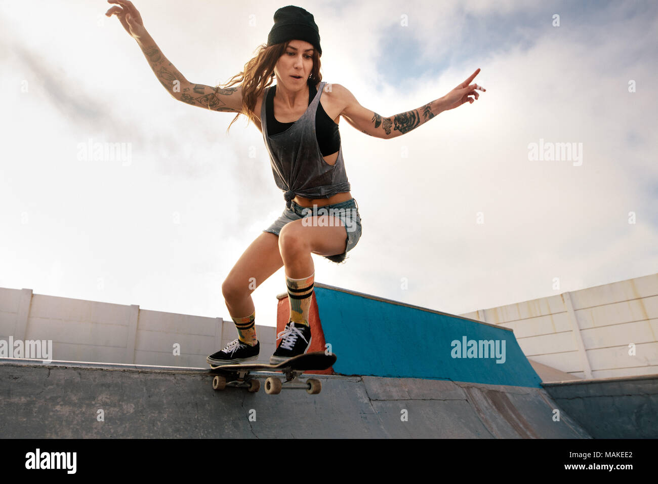 Cool giovane donna lo skateboard a skate park. Skater femmina a cavallo su skateboard. Foto Stock