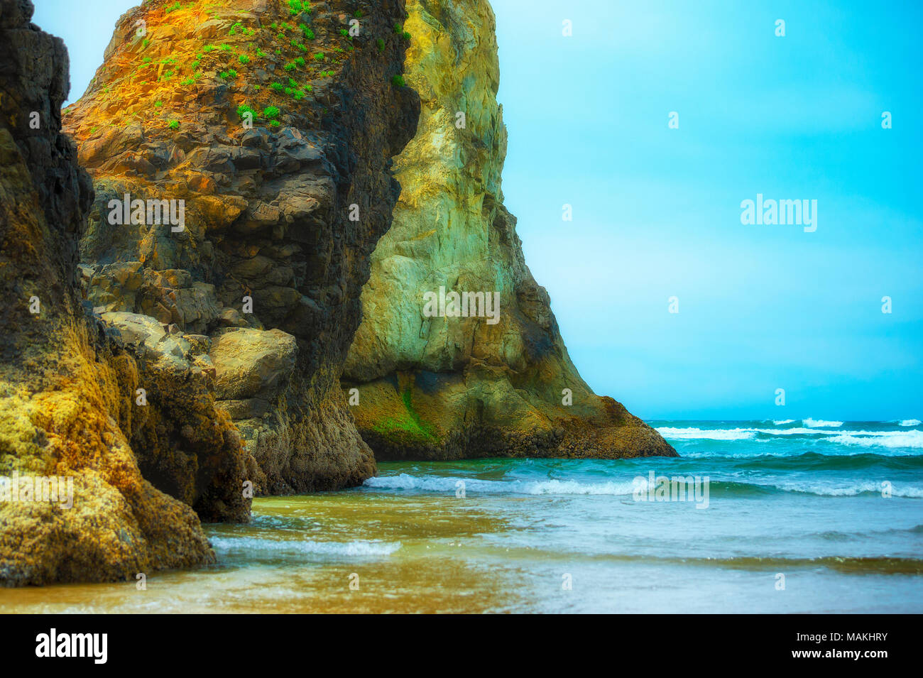 Piccole onde rotolo attorno ad enormi rocce e sulla spiaggia di Arcadia vicino a Cannon Beach, Oregon Foto Stock