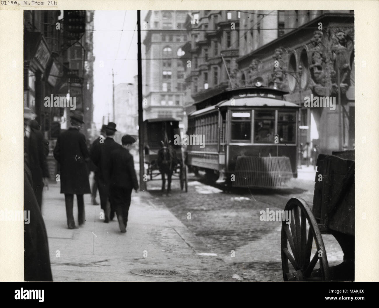In orizzontale e di fotografia in bianco e nero che mostra Olive Street guardando ad ovest dalla 6th Street. Alcuni uomini e un ragazzo di camminare lungo il marciapiede sulla sinistra e un vagone tirato da cavalli e tram unità verso la fotocamera sulla destra. Alti edifici commerciali di linea su entrambi i lati della strada, molti dei quali hanno ornato sculture in pietra o in mattoni e. Titolo: Olive Street guardando ad ovest dalla 6th Street. . Tra il 1908 e il 1909. Holt, Charles Clemente, 1866-1925 Foto Stock