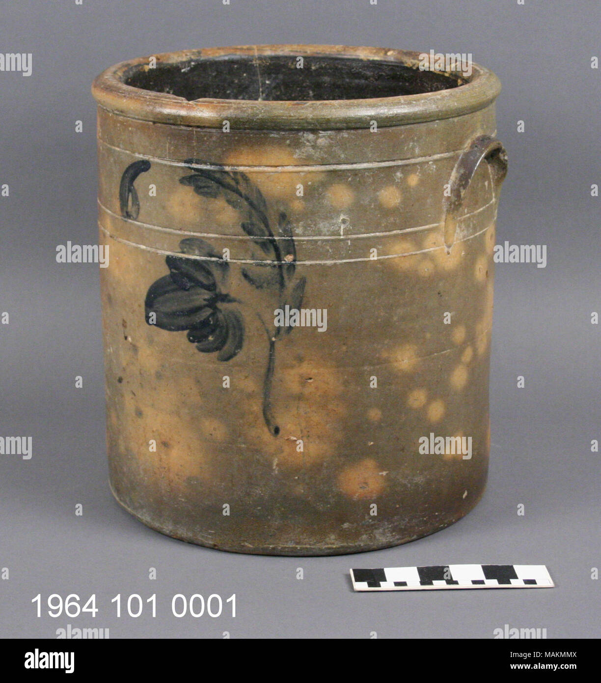 Marrone scuro cilindrico satinato coccio con disegno floreale in blu scuro smalto sulla parte anteriore. I lati sono paralleli con due piccole allegata Appendice maniglie. Labbro di spessore attorno all'ampia apertura. Interno smaltati in Albany slip. Dalla Baker station wagon. Titolo: Dark cilindrica di coccio con disegno floreale . circa 1850. Foto Stock