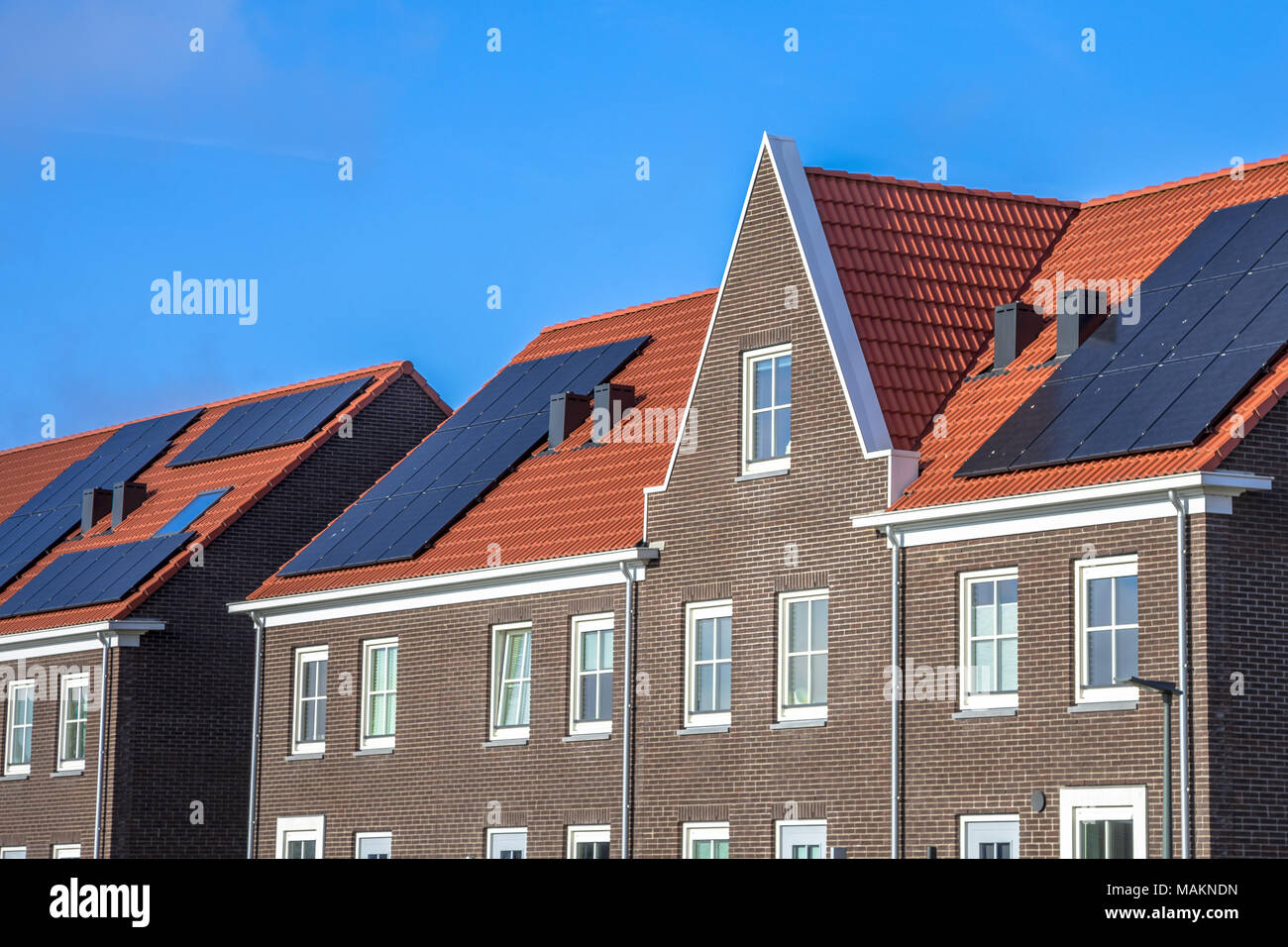 Chiudere da moderne ville a schiera con pannelli solari, marrone di mattoni e tegole rosse in stile neoclassico in Groningen Paesi Bassi Foto Stock