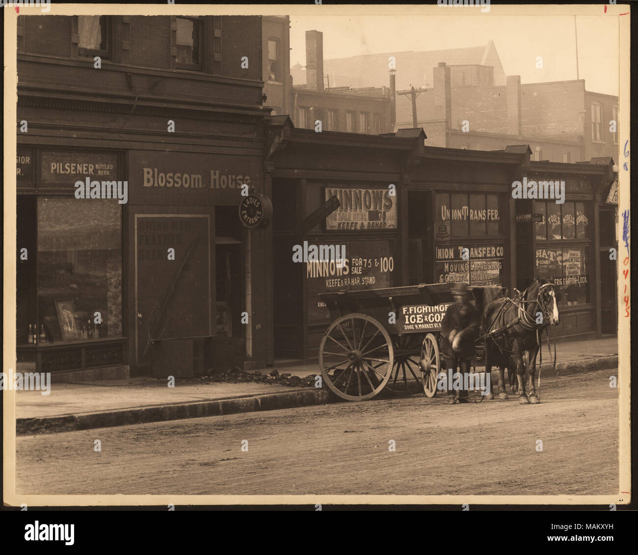 In orizzontale e di fotografia in bianco e nero di una fila di edifici commerciali e un vagone tirato da cavalli parcheggiato contro il marciapiede. Titolo: Driver lo scarico del carbone presso la casa di fiore. . Tra circa 1800 e circa 1900. Swekosky, William G., 1895-1964 Foto Stock
