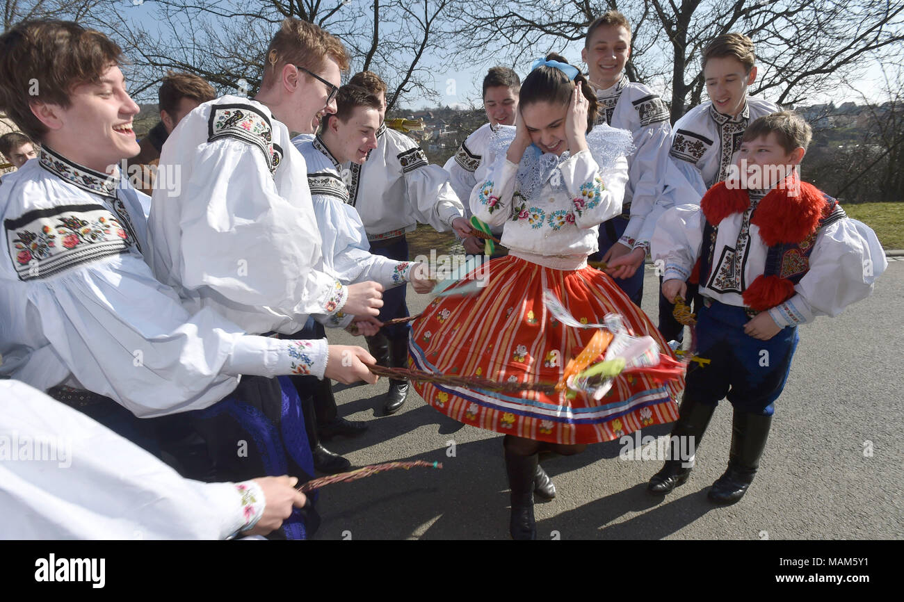 Giovani uomini in costumi folk frusta una ragazza con treccia di willow steli durante il lunedì di Pasqua le celebrazioni tradizionali in Vlcnov, nella Repubblica Ceca il 2 aprile 2018. L antica usanza di mantecazione di ragazze e donne con salice intrecciati di steli e li spruzzi di acqua fredda dovrebbe assicurare l'universo femminile con un buono stato di salute e di aspetto fresco. Le ragazze poi dare colorato o dipinto di uova per i ragazzi e gli uomini come un segno della loro grazie e perdono. (CTK foto/Dalibor Gluck) Foto Stock