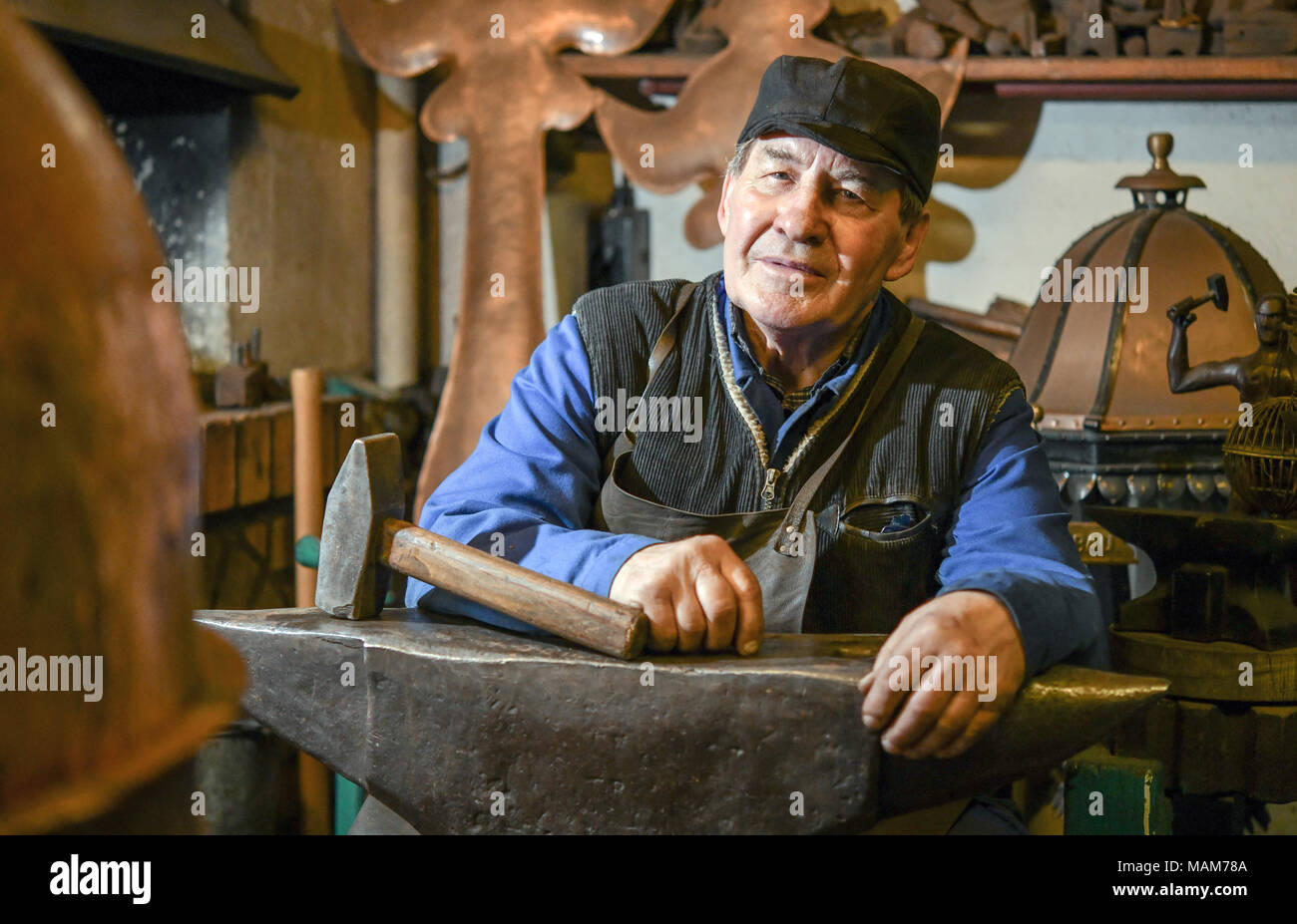 14 marzo 2018, Germania, Angermuende: Master builder di metallo Wilfried Schwuchow seduti dietro un'incudine nella sua bottega. Foto: Patrick Pleul/dpa-Zentralbild/ZB Foto Stock