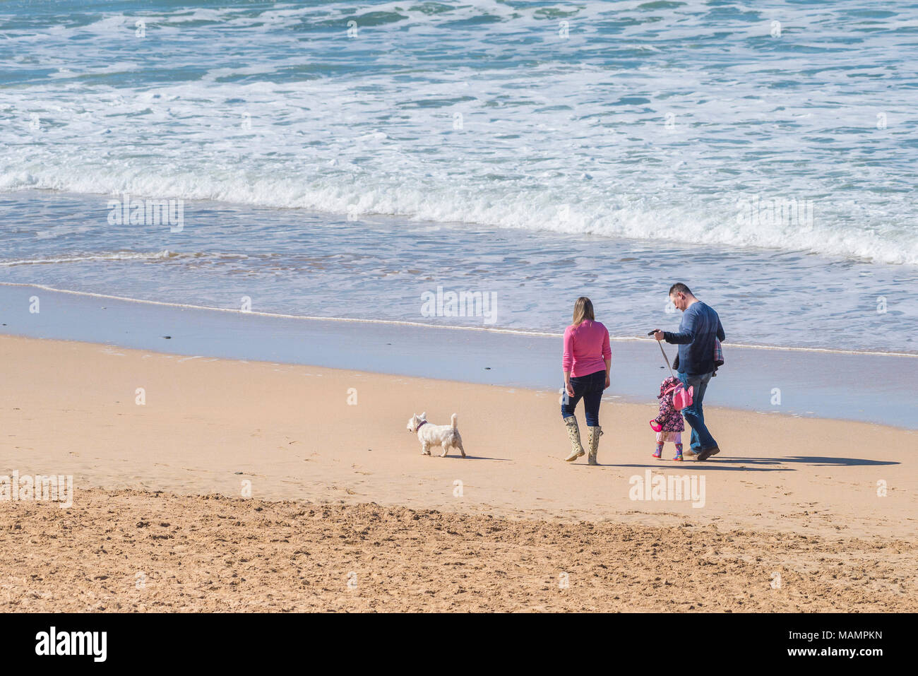 Una famiglia godendo il sole primaverile come essi passeggiata lungo il litorale su Fistral Beach in Newquay Cornwall. Foto Stock