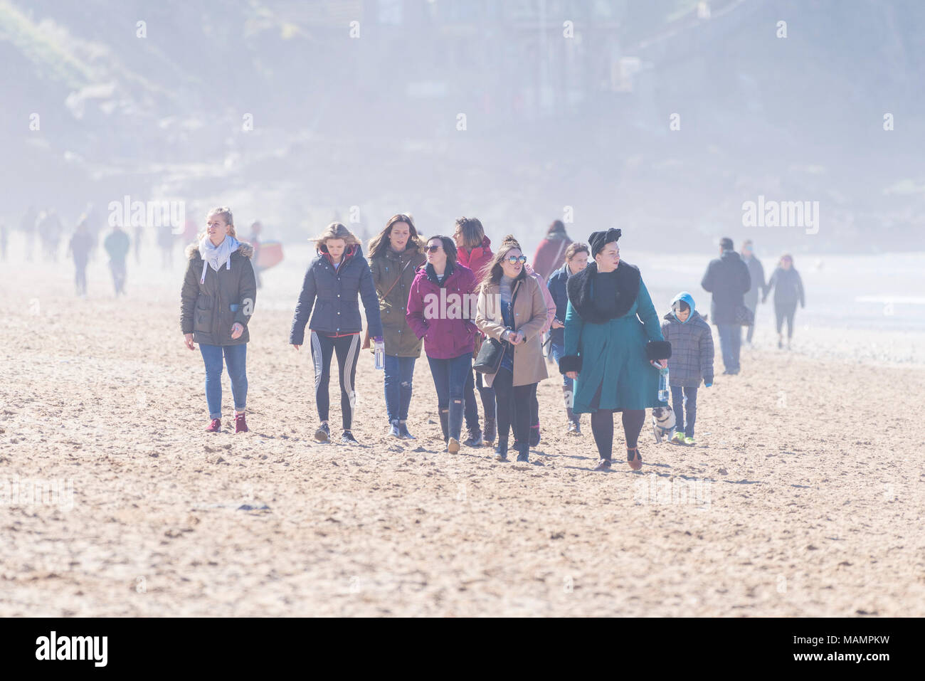 Un gruppo di giovani donne godendo di una passeggiata nel sole nebuloso sul Fistral Beach in Newquay Cornwall. Foto Stock