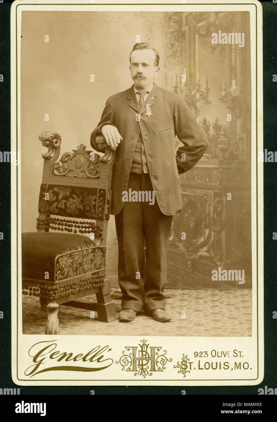 Formale a tutta lunghezza Ritratto di Henry Remzi indossa una tuta con una medaglia appuntata a camicia colletto, e in piedi con il suo braccio sinistro su una sedia. "Genelli' e '923 OLIVE ST. ST. LOUIS, MO." (stampato immagine sotto). Titolo: Henry Remzi (Unione veterano). . Circa 1892. Genelli, San Luigi Foto Stock