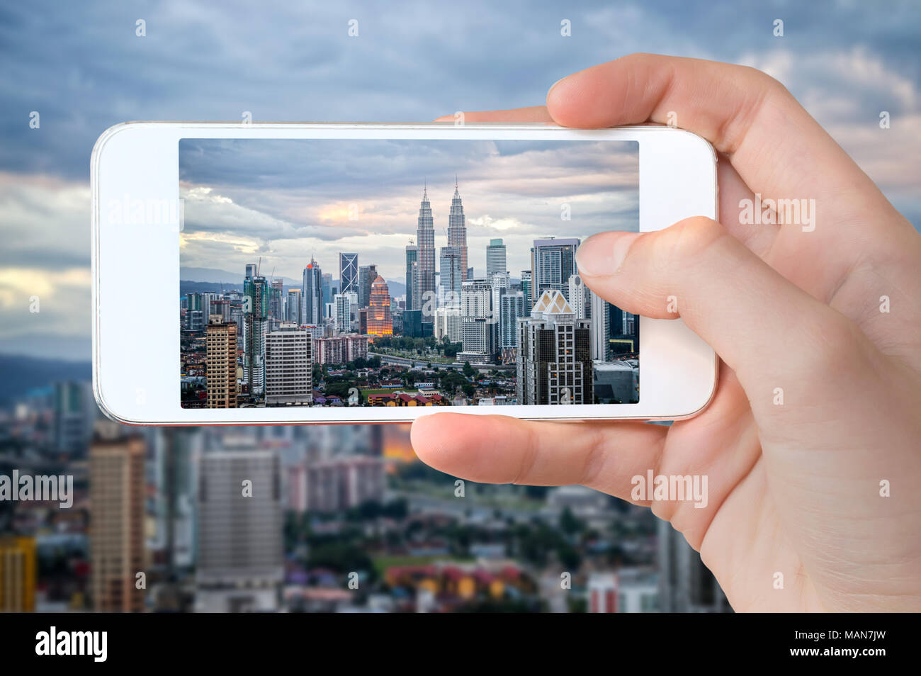 Primo piano di una mano con lo smartphone di scattare una foto dello skyline di Kuala Lumpur, Malesia Foto Stock