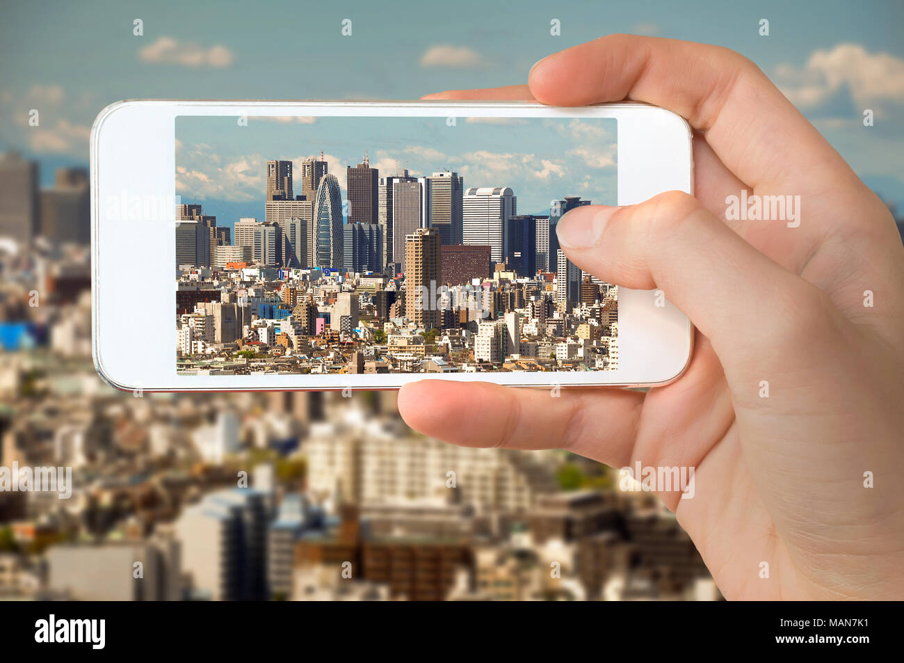 Primo piano di una mano con lo smartphone per scattare una foto della skyline di Tokyo, edifici di Shinjuku, Giappone Foto Stock