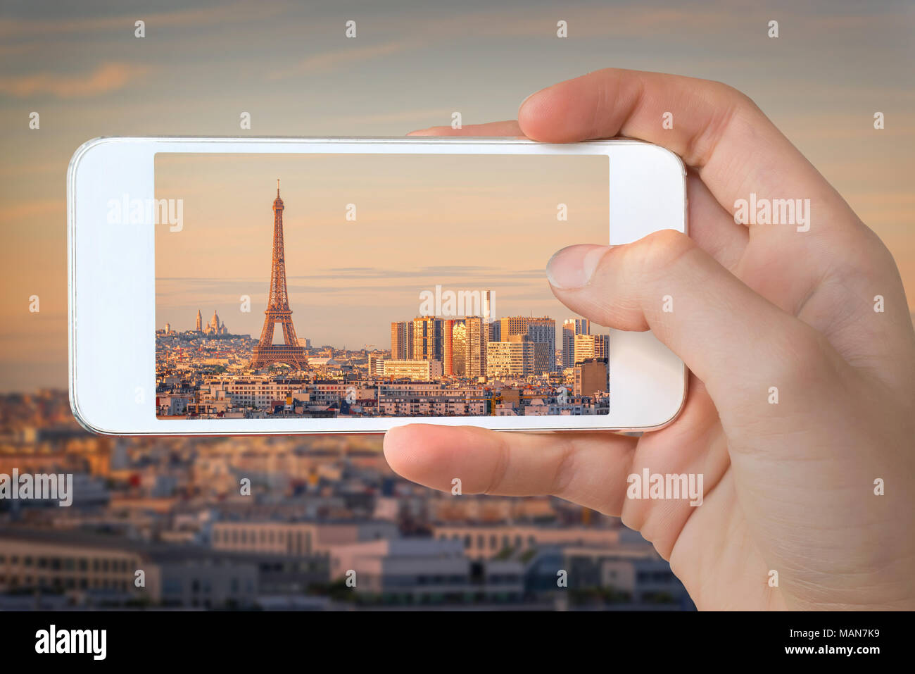 Primo piano di una mano con lo smartphone di scattare una foto di Parigi con la torre Eiffel al tramonto, Francia Foto Stock