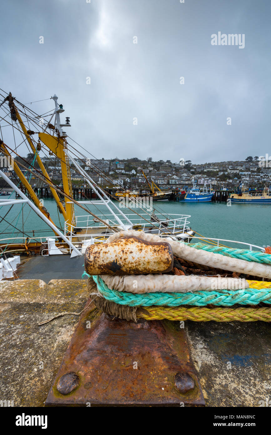 Funi legate ad un vecchio arrugginito bollard corrosi accanto alle attività di pesca i pescherecci con reti da traino nel porto dell'cornish fishingh città o villaggio di Newlyn. cornsih la pesca Foto Stock