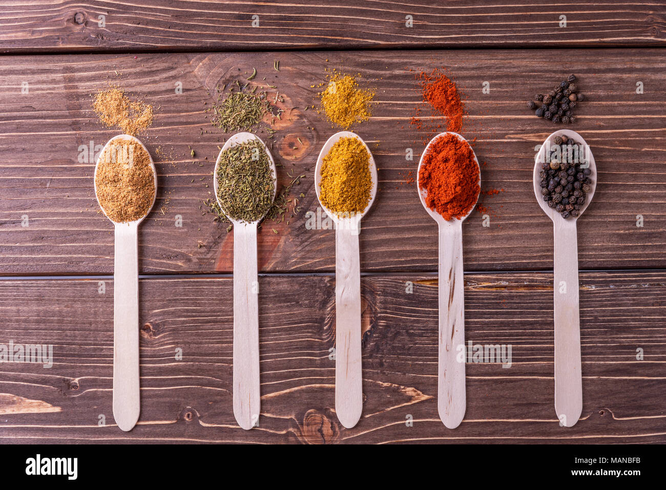 Assortimento di spezie colorate in i cucchiai di legno. Foto Stock