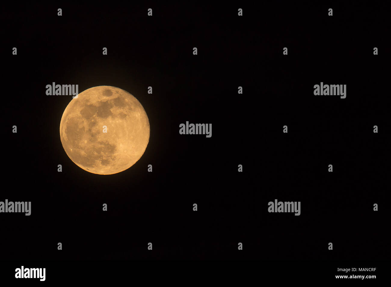 Blue Moon Rising il 31 marzo 2018, paesaggio orientate immagine con Luna isolata su sfondo nero con testo o copia di spazio. Foto Stock