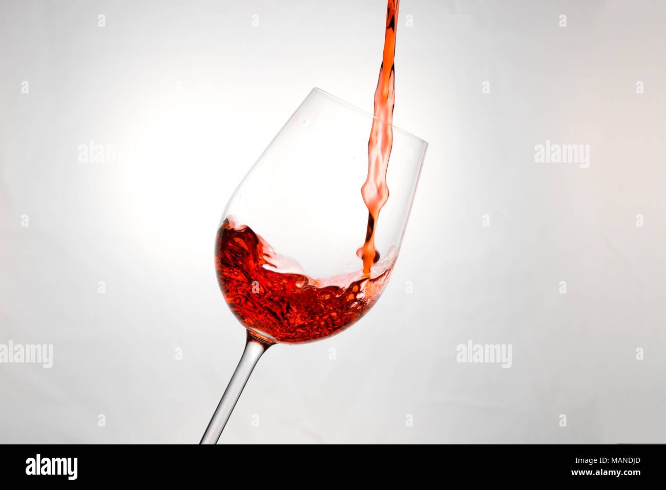 Rosso brillante liquido come il vino rosso, succo di fragola o qualcosa di simile, che viene versato in un bicchiere Foto Stock
