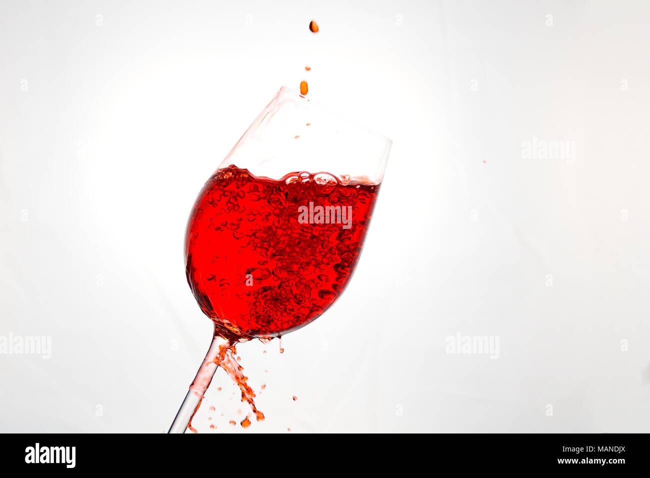 Vino rosso che viene versato in un bicchiere e schizzato intorno Foto Stock