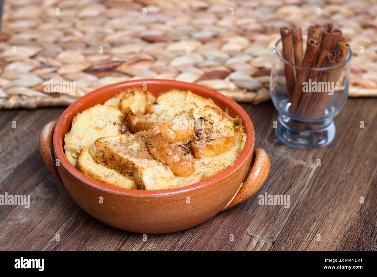 Pentola di coccio con i più diffusi i bambini dessert, pudding di pane. Decorate con bastoncini di cannella in un vasetto di vetro Foto Stock