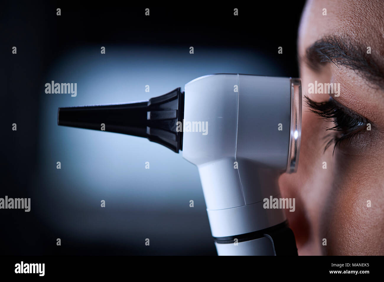 Medico donna utilizzando otoscopio, vista laterale, vicino fino Foto Stock