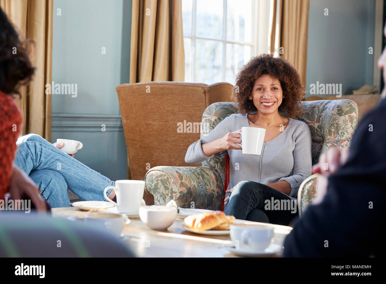 Donna di mezza età incontro con gli amici intorno al tavolo In Coffee Shop Foto Stock
