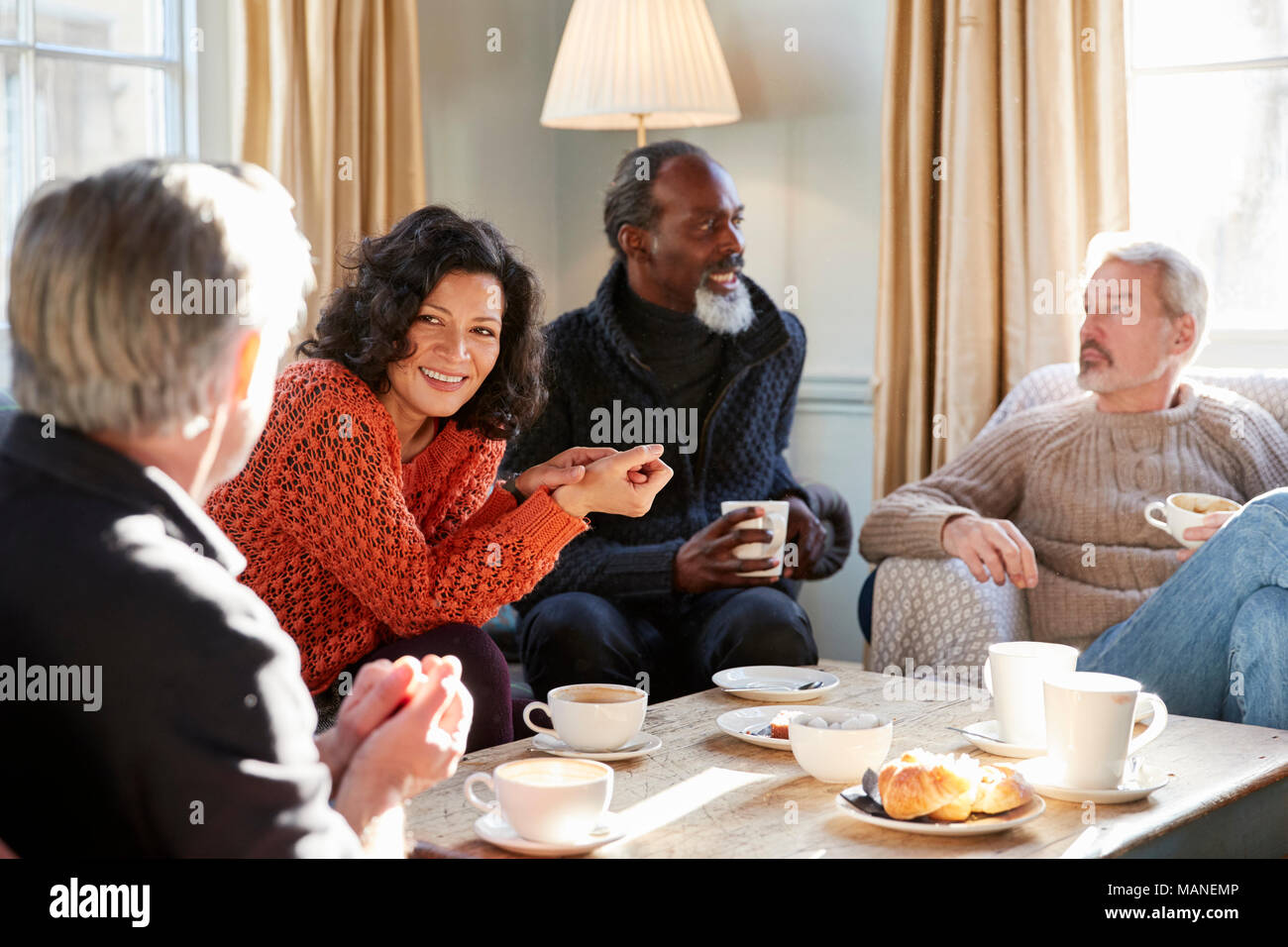 Un gruppo di persone di mezza età amici riuniti intorno al tavolo In Coffee Shop Foto Stock