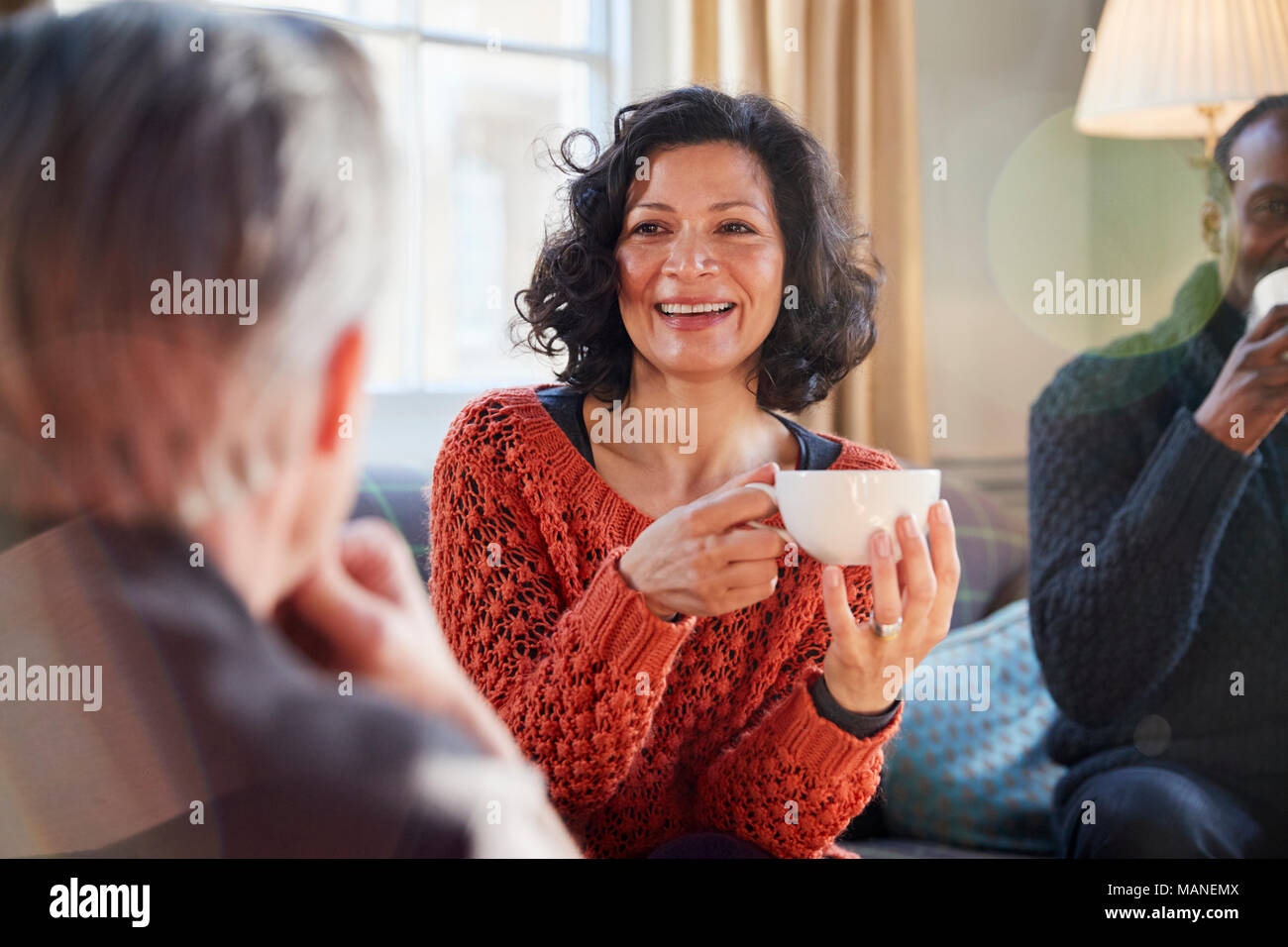 Donna di mezza età incontro con gli amici intorno al tavolo In Coffee Shop Foto Stock