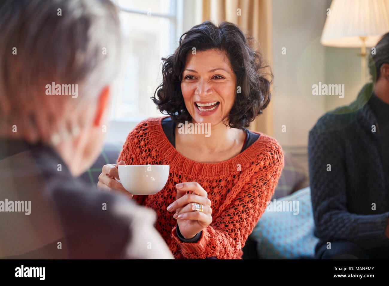 Donna di mezza età incontro con gli amici intorno al tavolo In Coffee Shop Foto Stock