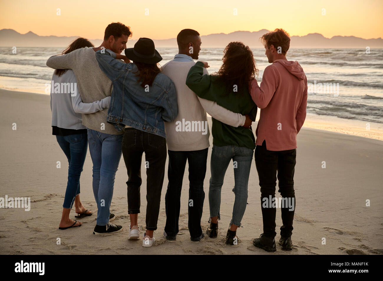 Gruppo di amici sulla Spiaggia Invernale la visione di insieme di Sunrise Foto Stock