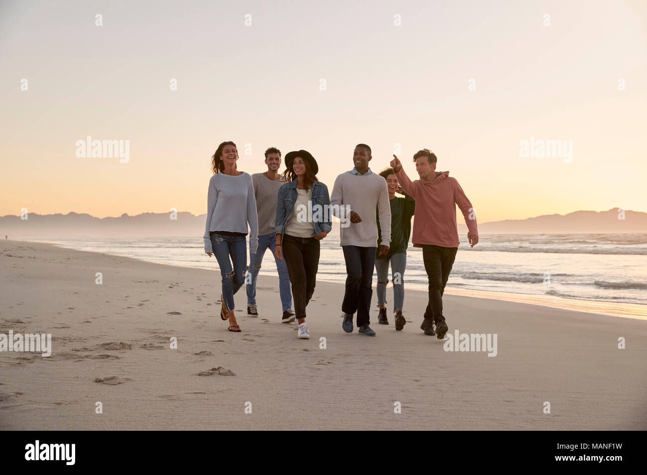 Gruppo di amici a camminare lungo la spiaggia invernale insieme Foto Stock