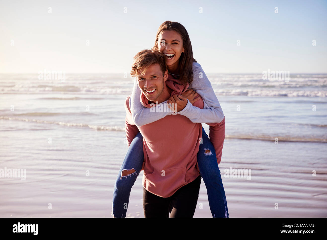 Uomo Donna dando piggyback sulla spiaggia invernale Vacanza Foto Stock