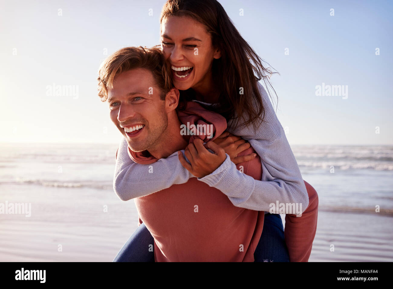 Uomo Donna dando piggyback sulla spiaggia invernale Vacanza Foto Stock